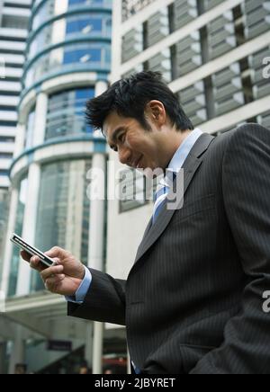 Chinese businessman text messaging on cell phone Stock Photo
