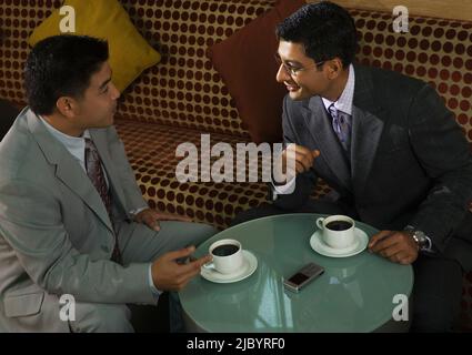 Businessmen drinking coffee together in cafe Stock Photo