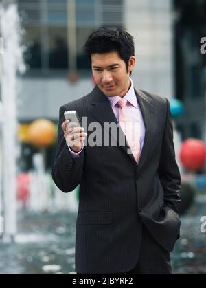 Chinese businessman text messaging on cell phone Stock Photo