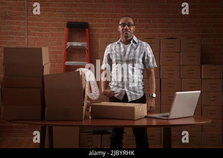 African American man with boxes and laptop Stock Photo
