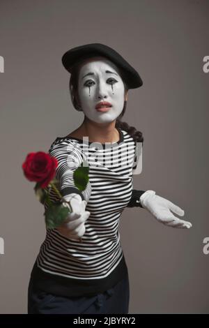 Woman in mime costume holding out rose Stock Photo