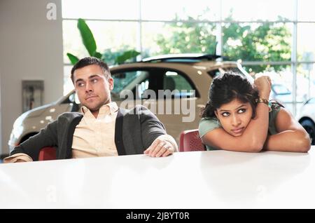 Frustrated couple sitting in car showroom Stock Photo