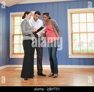 Couple talking with realtor in empty house Stock Photo