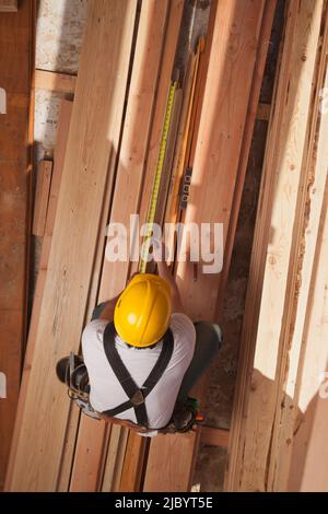 Mixed race construction worker measuring lumber Stock Photo