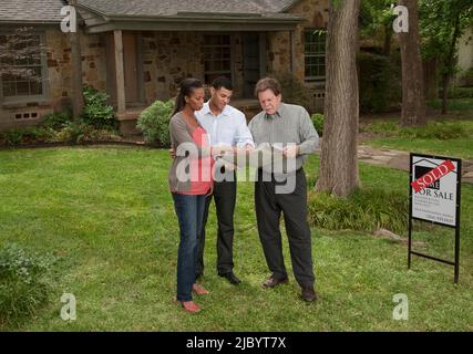 Couple standing with architect in yard of sold house Stock Photo