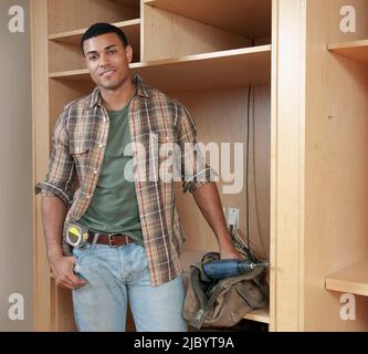 Mixed race man building cabinet Stock Photo