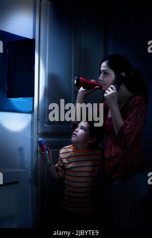 Hispanic mother and son checking fuse box Stock Photo