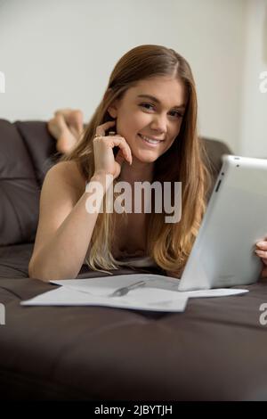 Woman using digital tablet to study on sofa Stock Photo