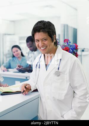 Asian male doctor leaning on counter Stock Photo