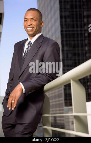 African businessman leaning on railing outdoors Stock Photo