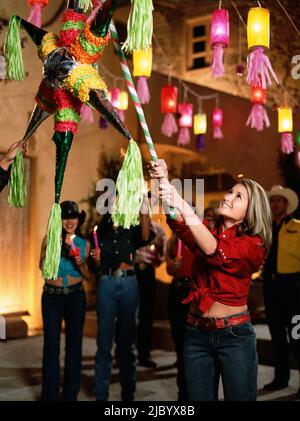 Mixed race woman hitting pinata Stock Photo