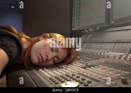 Caucasian woman sleeping on audio control panel Stock Photo