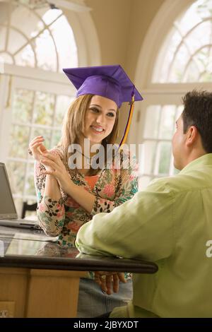 Father admiring daughter's graduation cap Stock Photo
