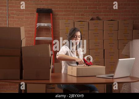 Hispanic woman taping cardboard box Stock Photo