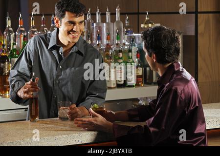 Hispanic male bartender talking to customer Stock Photo