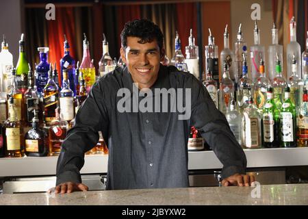 Hispanic male bartender leaning on bar Stock Photo