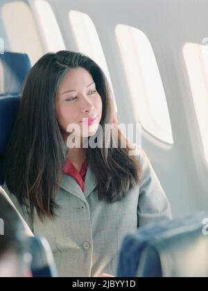 Asian woman looking out airplane window Stock Photo