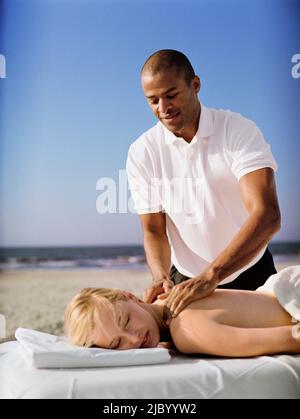 Woman receiving massage at beach Stock Photo