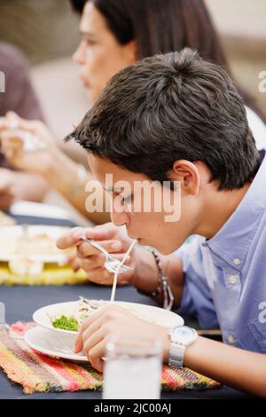 Teenage boy eating pasta Stock Photo