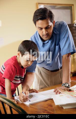 Indian father helping son with homework Stock Photo