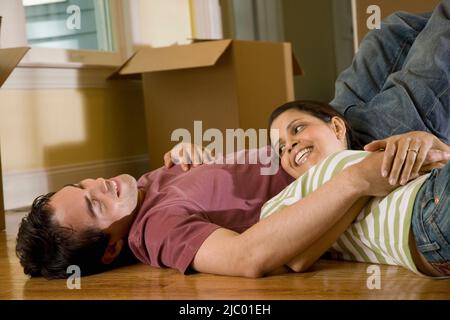 Hispanic couple on floor next to moving boxes Stock Photo