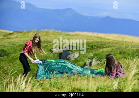 Camping and hiking. Summer adventures. Temporary housing. Camping trip. Helpful to have partner for raising tent. Camping skills concept. In middle of Stock Photo