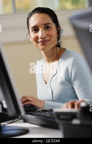 Businesswoman using a computer and talking on a headset Stock Photo