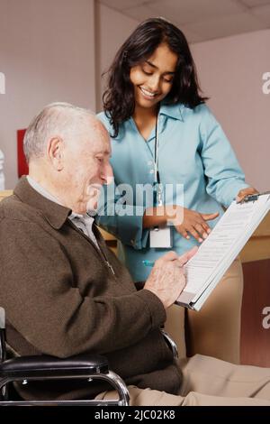 Nurse holding a form for an elderly man to sign Stock Photo
