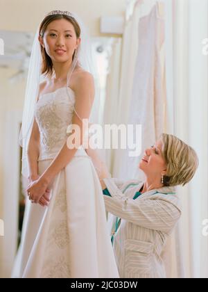 Young bride being fitted in her dress Stock Photo