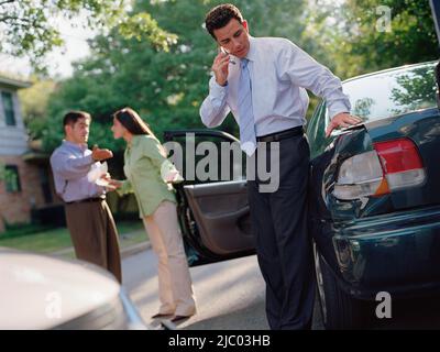 Businessman talking on his cell phone by a car accident Stock Photo