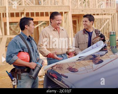 Manual workers examining blueprints Stock Photo