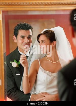 Newlywed couple looking at themselves in the mirror Stock Photo