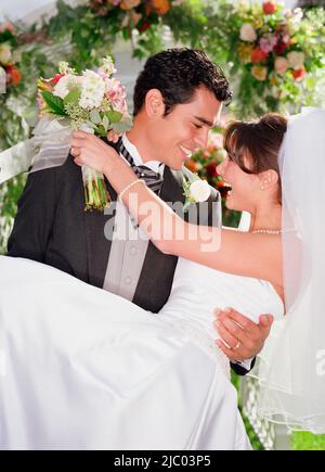 Groom holding his bride in his arms Stock Photo