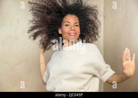A mixed race , middle-aged woman dancing with her hands out towards camera. Stock Photo