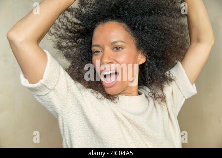 Close up portrait of a mixed race middle aged woman singing with her hands up in the air. Stock Photo
