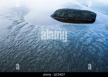 Sand patterns and a pool of water with a rock in it on Tonquin Beach  near Tofino, BC, Canada. Stock Photo