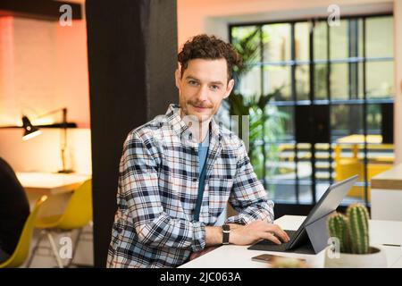 Young man in co-working space working on tablet Stock Photo
