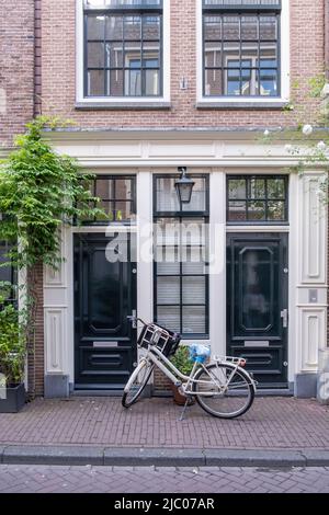 Amsterdam house, traditional red brick facade, bicycle parked outside. Building in residential neighborhood, Holland Netherlands Stock Photo