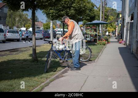 Temerin, Serbia, Jun 1, 2022: Senior citizen loading bicycle with shopping bags Stock Photo