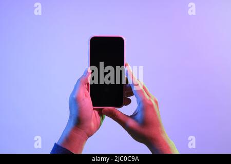 The Asian man hands holding the smart phone under the vivid color. Stock Photo