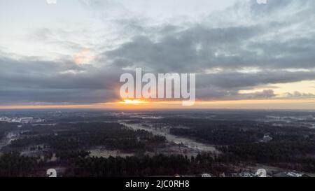 Rijkevorsel, Belgium, 28th of January, 2022, dramatic and colorful sunrise or sunset sky over the Little village of Sint Jozef, on the canal Dessel Schoten aerial photo in Rijkevorsel, kempen, Belgium, showing the waterway in the natural green agricultural landscape. High quality photo. High quality photo Stock Photo