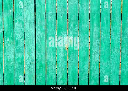 Old wooden worn fence boards weathered texture in peeling green paint. Space for inscriptions or objects. Stock Photo