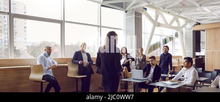 Various businessmen listen to female business leader during corporate meeting or training lecture. Stock Photo