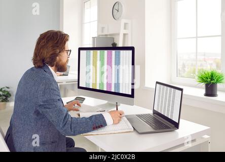 Serious male accountant in office working with software for electronic invoices on computer. Stock Photo