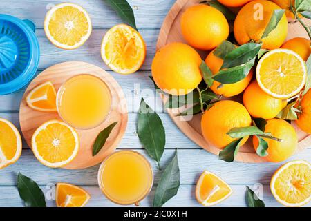 Fruit squeezer and ripe fresh oranges on blue wooden table top, fresh orange juice making, overhead Stock Photo