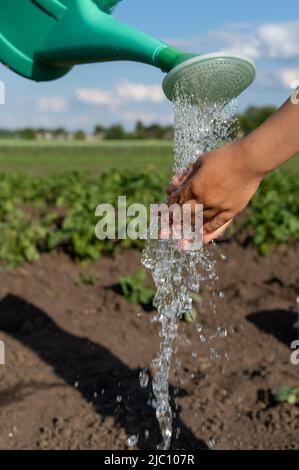 Little girl washes her hands under running water in nature. A stream of water flows into the hands of a girl. Drops of water sprayed in hands close-up Stock Photo