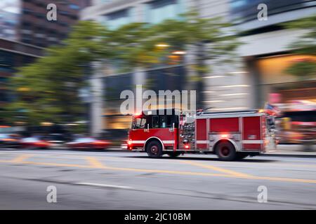 Fast moving fire engine on city street. Firefighters in blurred motion. Themes rescue, urgency and help. Stock Photo