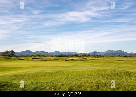 Golf course behind the sand dunes at Harlech beach with spectacular views of the mountains of Snowdonia, North Wales. Stock Photo