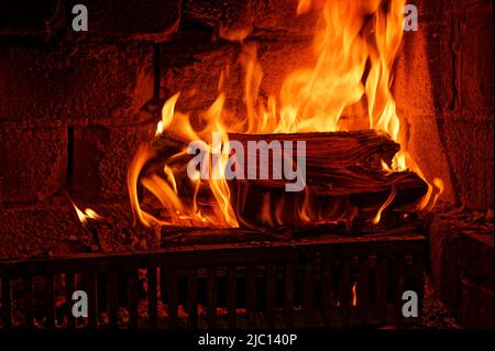 Flames are licking around a large piece of water in an open fire grate Stock Photo