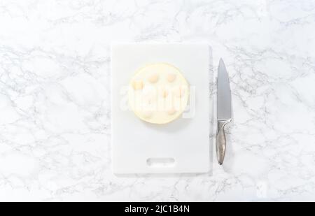 Flat lay. Cutting hard-boiled eggs in a shape of a loaf on a white cutting board. Stock Photo